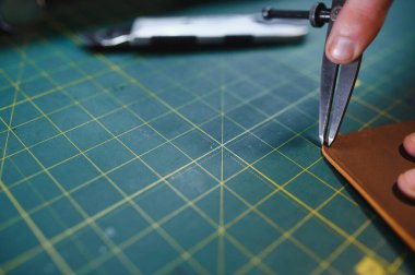 Deriyle çalışan bir adam. Profesyonel bir cüzdan yapar. Erson kumaşı ölçer..