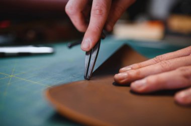 Deriyle çalışan bir adam. Profesyonel bir cüzdan yapar. Erson kumaşı ölçer..