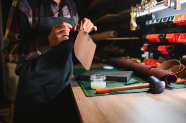 Erkek zanaatkar profesyonel deri atölyesinde dikkatlice deri parçalarını yumrukluyor..