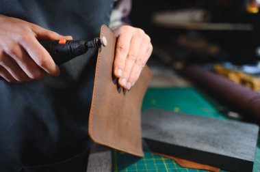 Deri ustası, bir müşteri için deri bir ürün yapmak için özenle hazırlanır. Deri ustası konsepti.