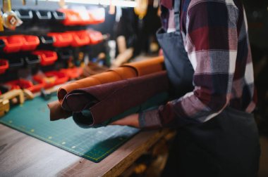 Terzi turtası farklı rulo tutuyor. Doğal kahverengi deri, atölyede çalışıyor. Sanayi Sanayi Sanayi İşletme Ustası.