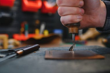 Deriyle çalışan bir adam. Profesyonel bir cüzdan yapar. Erson kumaşı ölçer..
