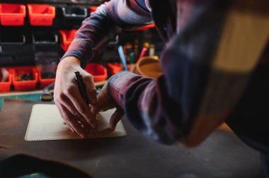 Deri ustası, bir müşteri için deri bir ürün yapmak için özenle hazırlanır. Deri ustası konsepti.