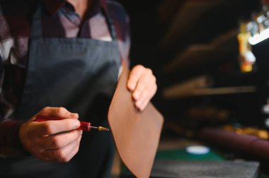Üretim süreci. Genç odaklı usta zanaatkar işyerinde deri ürünler yapıyor..