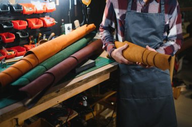 Terzi turtası farklı rulo tutuyor. Doğal kahverengi deri, atölyede tekstil ile çalışıyor. Sanayi Sanayi Sanayi İşletme Ustası.