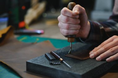 Üretim süreci. Genç odaklı usta zanaatkar işyerinde deri ürünler yapıyor..