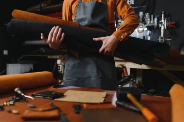 Terzi turtası farklı rulo tutuyor. Doğal kahverengi deri, atölyede tekstil ile çalışıyor. Sanayi Sanayi Sanayi İşletme Ustası.