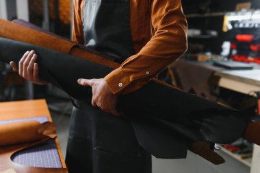 Terzi turtası farklı rulo tutuyor. Doğal kahverengi deri, atölyede çalışıyor. Sanayi Sanayi Sanayi İşletme Ustası.
