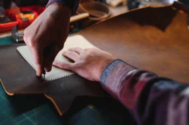 Deriyle çalışan bir adam. Profesyonel bir cüzdan yapar. Erson kumaşı ölçer..