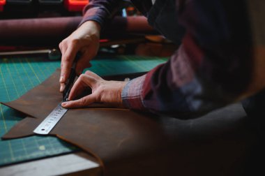 Deriyle çalışan bir adam. Profesyonel bir cüzdan yapar. Erson kumaşı ölçer..