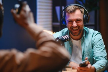 Konukla röportaj yapmak için yüksek teknolojili mikrofonlar kullanarak podcast kaydeden adam, izleyiciler için kusursuz video ve ses kalitesi sağlıyor.