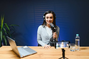 Kameraya bakan kadın vlogger etkileyicisi, genç kadın blogger hayranlarını selamlıyor ve akıllı telefona bakarak konuşuyor, çevrimiçi video konferansına katılıyor.