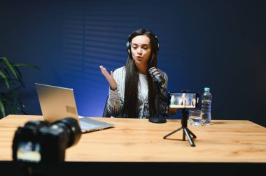 Kameraya bakan kadın vlogger etkileyicisi, genç kadın blogger hayranlarını selamlıyor ve akıllı telefona bakarak konuşuyor, çevrimiçi video konferansına katılıyor.