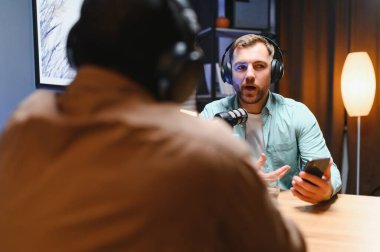 Konukla röportaj yapmak için yüksek teknolojili mikrofonlar kullanarak podcast kaydeden adam, izleyiciler için kusursuz video ve ses kalitesi sağlıyor.