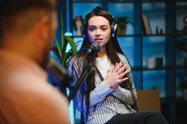 Profesyonel mikrofonlarla kayıt yaparken podcast röportaj yapan başarılı kadının yan görünümü, kopyalama alanı.