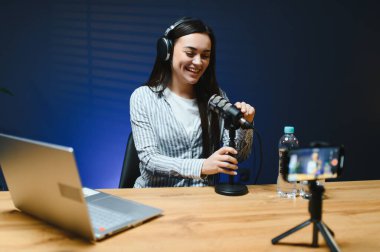 Kameraya bakan kadın vlogger etkileyicisi, genç kadın blogger hayranlarını selamlıyor ve akıllı telefona bakarak konuşuyor, çevrimiçi video konferansına katılıyor.