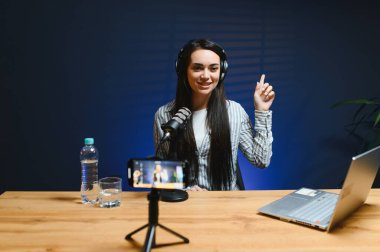 Smiling young caucasian girl woman making a video blog (vlog) with camera clipart