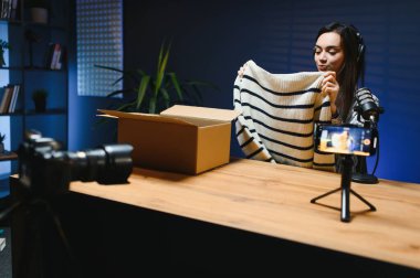 Dişi bir vlogger kameraya yeni şık giysiler yerleştiren bir video kaydediyor..