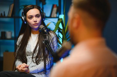 Canlı yayında sunucu kadınla röportaj yapıyor, moda ve tarz trendleri hakkında konuşuyor, fikirlerine katılmıyor. Adam sosyal medya ünlüleriyle tartışıyor, podcast kaydediyor.