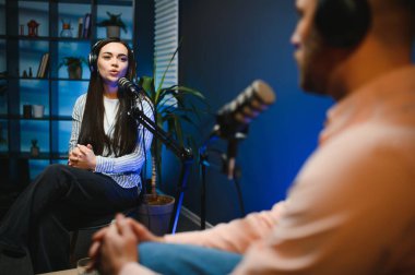Profesyonel mikrofonlarla kayıt yaparken podcast röportaj yapan başarılı kadının yan görünümü, kopyalama alanı.