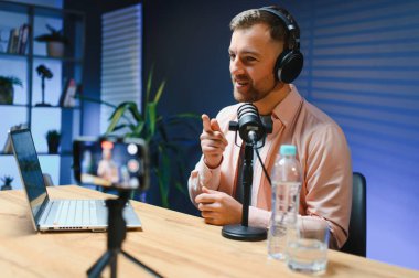 Stüdyoda canlı yayın yapmak için akıllı telefon kullanıyor. Sosyal medya yayıncılığı kariyeri için cep telefonu, mikrofon ve kulaklık kullanan blog yazarı.