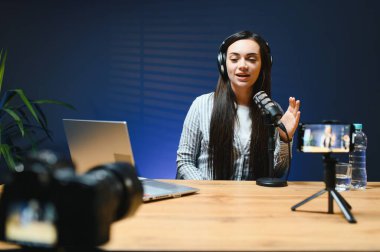 Smiling young caucasian girl woman making a video blog (vlog) with camera clipart