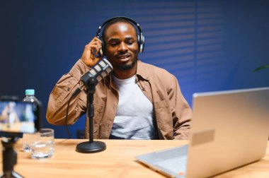 Siyah vlogger stüdyoda akıllı telefondan podcast çekiyor. Afro-amerikan etkileyicisi telefon ekranına bakıyor ve iyi haberleri seyircilere ve abonelere veriyor. Neşeli blogcu