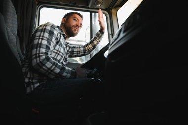 Kamyonun kabinindeki direksiyonun arkasındaki profesyonel sürücünün yan görüntüsü..