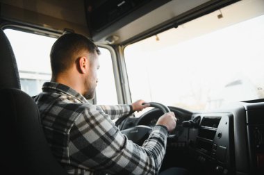 Kamyonun kabinindeki direksiyonun arkasındaki profesyonel sürücünün yan görüntüsü..