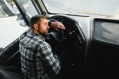 Karavanı boşaltılırken uzun bir yolculuktan sonra yorgun bir kamyon şoförü arabada uyuyor..