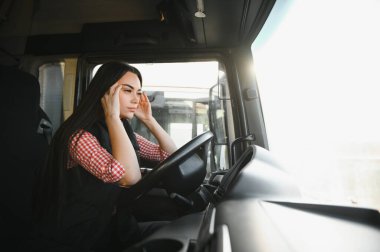 Uykulu ve yorgun kamyon şoförü. Kadın kamyoncu, direksiyon başında yorulduğu için esniyor..