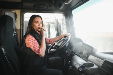 Kadın bir kamyon şoförü, bir kamyonun direksiyonunda elektronik sigara içiyor..