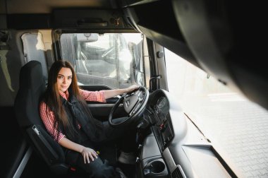 Büyük bir kamyon süren profesyonel bir kadının portresi. Aracın içinde. Kadın bir kamyoncu. Halk ve endüstriyel ulaşım kavramı.