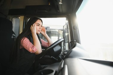 Uykulu ve yorgun kamyon şoförü. Kadın kamyoncu, direksiyon başında yorulduğu için esniyor..
