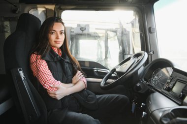 Büyük bir kamyon süren profesyonel bir kadının portresi. Aracın içinde. Kadın bir kamyoncu. Halk ve endüstriyel ulaşım kavramı.