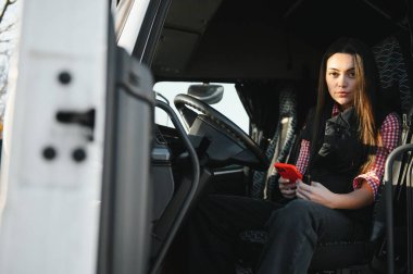 Kamyon kabininde elleri direksiyonda oturan kamyoncunun portresi..