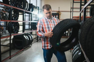 Akıllı erkek müşteri süpermarkette satın almak için yeni lastik seçimi. Araba mal ile büyük alışveriş merkezi.