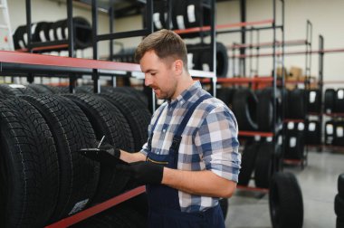 Yeni bir araba lastiği dükkanında çalışan bir işçinin portresi. Lastik değiştirme kavramı.