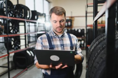 Lastik tamircisinin portresi. Geniş bir depo ya da çeşitli araba lastikleri..