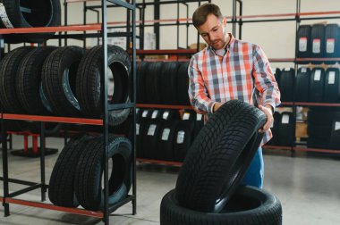 Adam araba tamirhanesinde kış lastiklerini seçiyor..