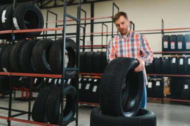Adam araba tamirhanesinde kış lastiklerini seçiyor..