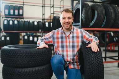 Adam araba dükkanında lastik seçiyor..