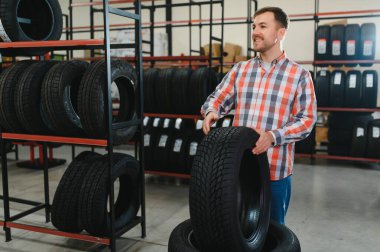 Adam araba tamirhanesinde kış lastiklerini seçiyor..