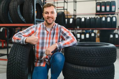 Erkek, markette araba lastiği üzerinde çalışıyor, günlük kıyafet giyen adam lastiğe bakıyor, seçimini yapıyor. alışveriş zamanı.