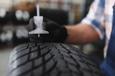 Araba servisindeki işçi lastiği montajı, otomobil tamircisi güvenlik için lastiği ve lastik lastiği kontrol ediyor, konsept: makinelerin onarımı, hata tanısı, onarım. Adam araba tamirhanesinden alışveriş yapıyor.