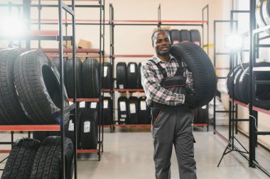 Lastikleri olan profesyonel bir Afrikalı Amerikalı işçi. Lastik tamir servisinde adam var..