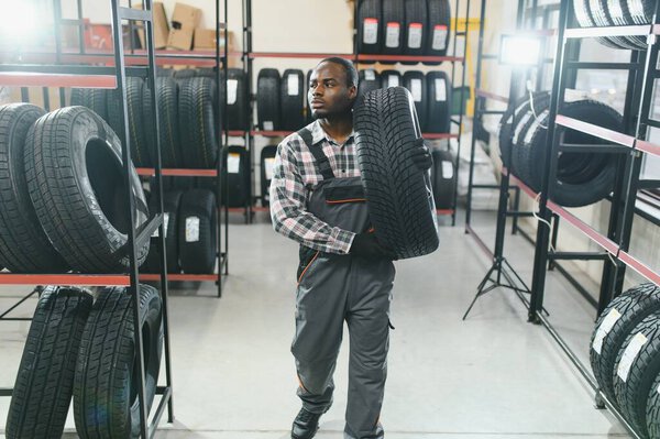 Портрет счастливого африканского автомеханика на фоне концепции галочки по шинам.