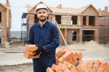 Construction worker in uniform and safety equipment have job on building. Industrial theme.