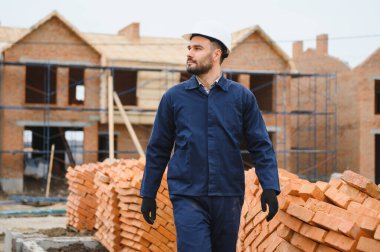 Üniformalı inşaat işçisi ve güvenlik ekipmanı inşaatında çalışıyor.