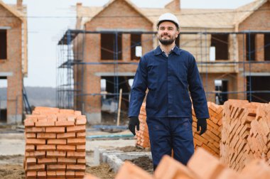 Construction worker in uniform and safety equipment have job on building. Industrial theme.